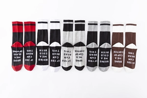 Détail de cinq paires de chaussettes en coton avec des phrases drôles sous la semelle