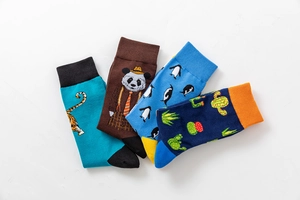 Flat lay of four colorful cotton socks with tiger, panda, penguin, and cactus patterns