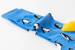 Close-up of blue knit socks with penguin patterns and yellow toe detail showing fabric texture