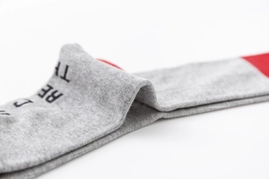 Macro shot of light grey cotton sport sock with red accent and printed text detail