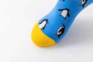 Detail of blue knit socks with yellow toe caps and cute penguin pattern print