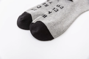 Vue détaillée des chaussettes de sport en coton gris avec pointe noire et motifs lettrés