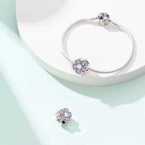 Detail of silver snake chain bracelet with pink heart-shaped petals and blue center stone