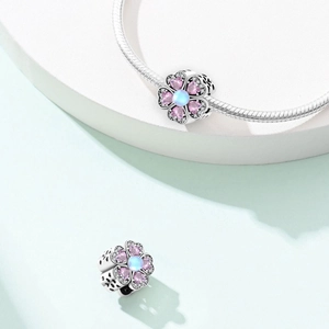 Detail of flower charm with pink heart zircons and blue moonstone on silver bracelet
