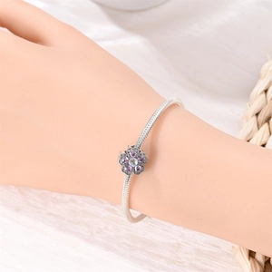 Detailed view of floral pendant on snake chain bracelet with purple zircon and opal stones