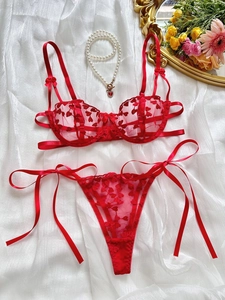 Détails d'un ensemble lingerie en dentelle rouge avec broderie coeur et nœuds satin