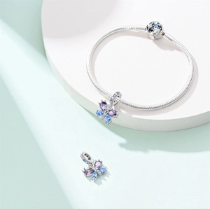 Close-up of a silver snake chain bracelet with purple zircon butterfly charms on a stand