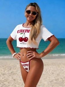 Close-up of cherry print graphic and red lettuce edge detail on white crop top