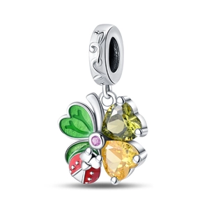 Macro detail of silver charm pendant with clover, ladybug, and heart-shaped zircons