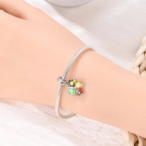 Detail of silver snake chain bracelet with flower pendant and tiny red ladybug charm