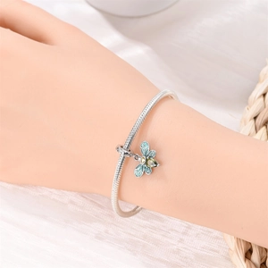 Detail of S925 silver snake chain bracelet featuring a blue enamel bee charm with green gemstone