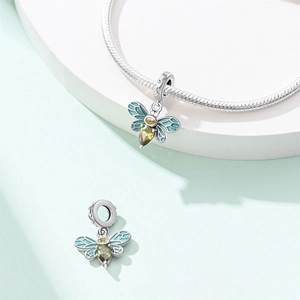 Macro detail of silver bee charm with green enamel wings and pear-cut zircon stones