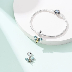 Detailed view of silver charm bracelet featuring blue enamel bee pendants and green stones