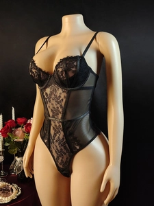 Dettaglio del body in pizzo floreale nero con trama a rete su un manichino elegante