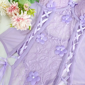 Detail of purple lace bodysuit with 3D floral accents, pearls, and ribbon lacing