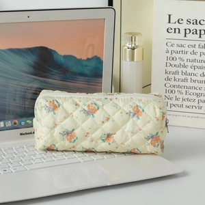 Quilted floral makeup bag with orange and purple flowers placed on a laptop keyboard