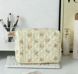 Quilted floral makeup bag with orange and blue flower pattern on a white keyboard