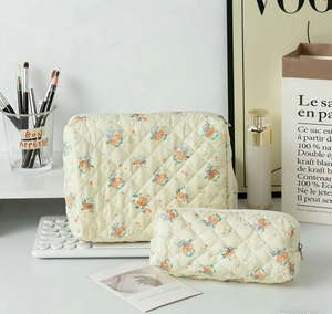 Close-up of a 2-piece quilted floral makeup bag set in cream cotton with zipper detail