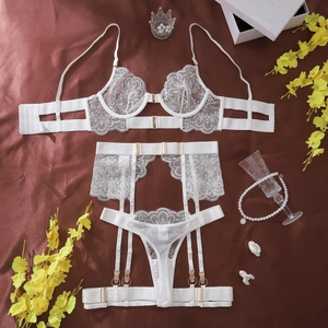 Flat lay of white lace lingerie set with floral embroidery on silk background