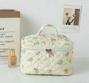 Detail of floral quilted makeup bag featuring dual zippers and top carry handle