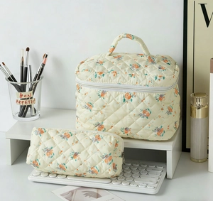 Quilted floral makeup bag set with top handle and matching pencil case on a desk