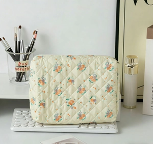 Detail of quilted floral makeup bag with orange and blue flowers next to a keyboard