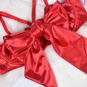 Detail of red satin lingerie with a large decorative bow and adjustable straps