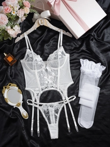 Detailed flat lay of white floral lace lingerie set with suspenders and stockings