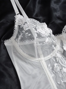 Close-up of white floral embroidery lace on a wired corset top with adjustable straps