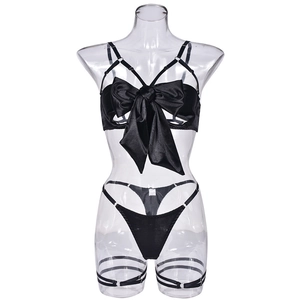 Detailed close-up of a black satin lingerie set featuring a large bow and metallic rings