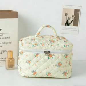 Quilted floral makeup bag with cream base, orange flower patterns and sturdy top handle