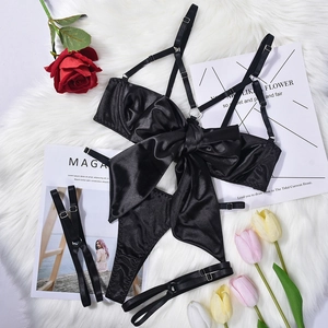 Flat lay of black satin lingerie set with large bow detail on faux fur and roses