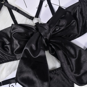 Detailed close-up of a black satin lingerie piece with a large decorative bow and silk texture