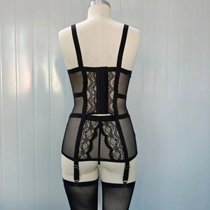 Detail of black lace corset with adjustable straps and garter attachments on mannequin