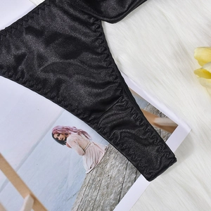 Close-up of black satin lingerie fabric showing smooth texture and fine zigzag stitching
