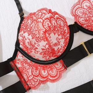 Close-up of red floral embroidery on sheer mesh fabric with black adjustable straps