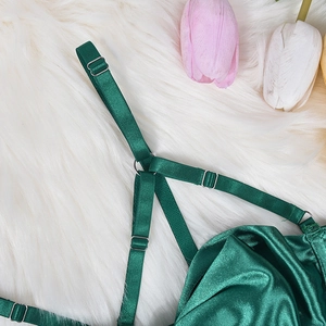 Detail of dark green satin lingerie with adjustable straps and silver metal buckles