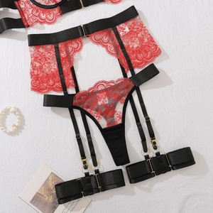 Macro detail of red floral lace garter belt set with black straps and gold buckles