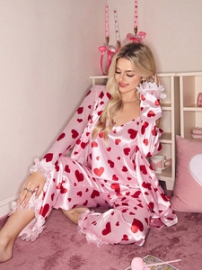 Detailed view of pink satin pajamas with heart print and layered lace trims on cuffs