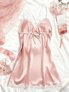 Detailed view of pink satin nightgown with white lace trim and crisscross back straps