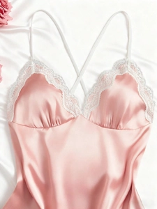 Close-up of pink satin nightdress with delicate white lace trim and criss-cross straps