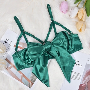 Detail of emerald green satin bra featuring a large bow and adjustable criss-cross straps
