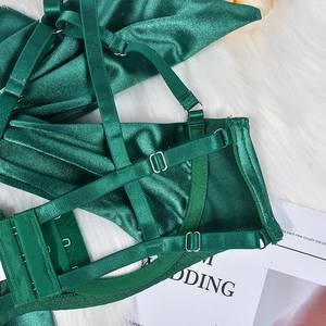 Detailed view of dark green satin lingerie with adjustable straps and silver metal buckles
