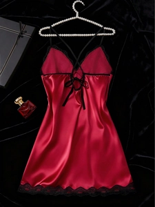 Close-up of wine red satin lingerie with black lace trim and cross-strap back detail
