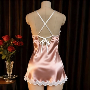 Close-up of pink satin nightdress back with white crisscross straps and lace trim