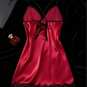 Red satin chemise with black lace trim and crossover back straps on dark background