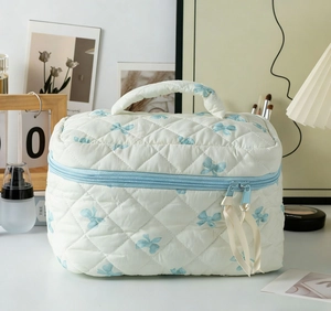 Detail der weiß gesteppten Kosmetiktasche mit blauen Schleifen und Doppelreißverschluss