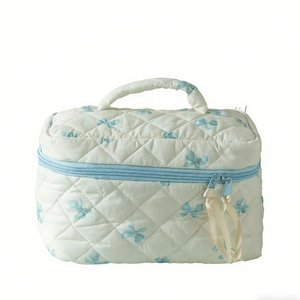 Gesteppte Kosmetiktasche mit blauen Schleifenmustern und hellblauen Reißverschlüssen auf Weiß