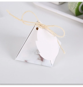 Detailed view of pyramid gift box with marble texture and leaf-shaped tag tied with twine
