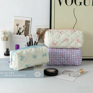Detail of quilted and checkered makeup bags with bow patterns and zipper closure